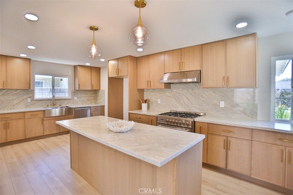 6401 Royal Oak Drive Huntington Beach, CA 92647 - Photo 30 of 49 a kitchen with a stove a sink a refrigerator and white cabinets with wooden floor
