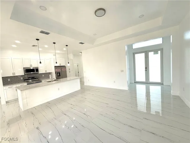 a large kitchen with kitchen island a refrigerator a stove a oven a center island with wooden floor