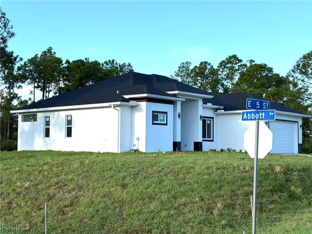 a front view of house with yard and trees in the background