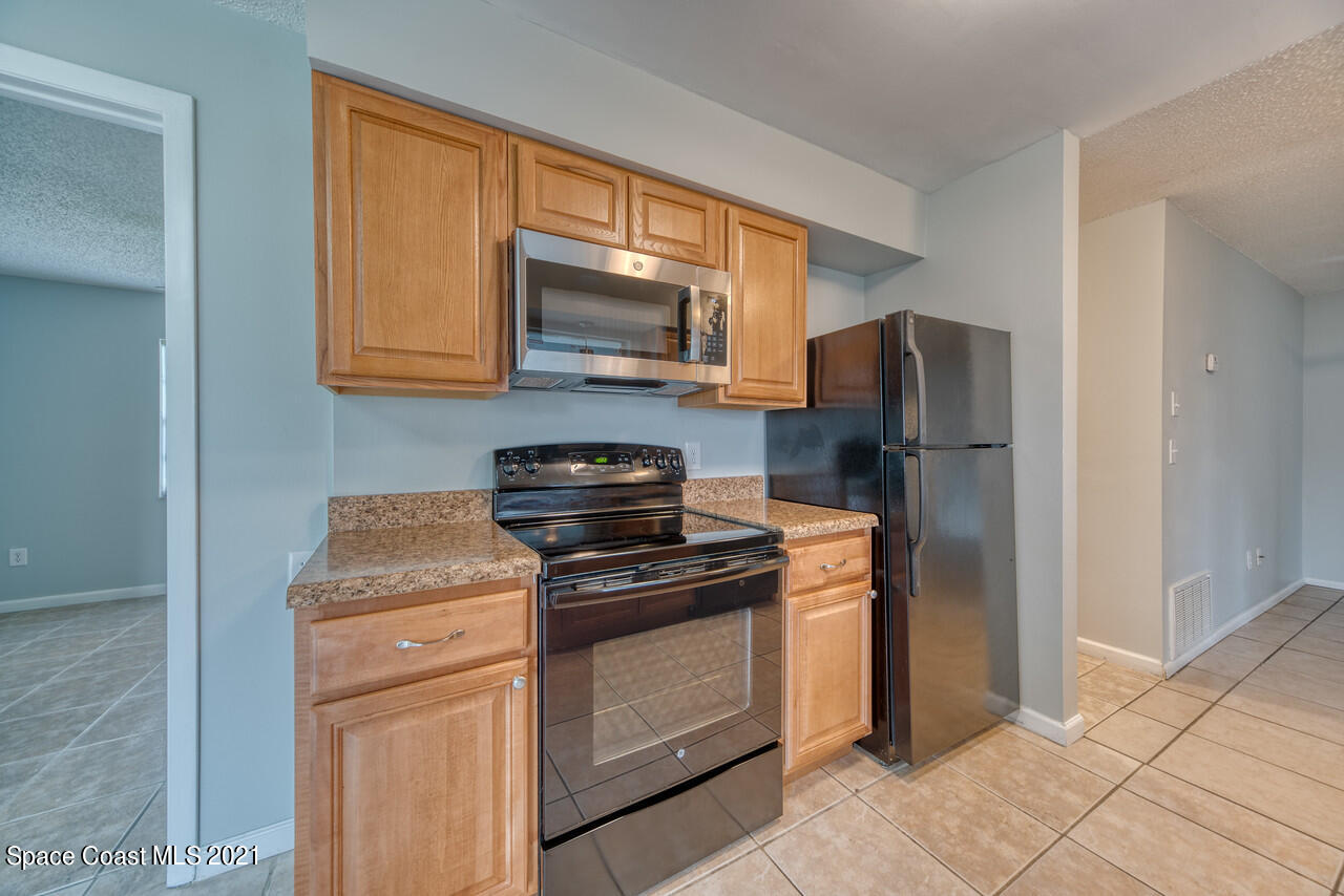 553 Edward Road West Melbourne, FL 32904 - Photo 16 of 26 a kitchen with stainless steel appliances granite countertop a stove a refrigerator and a microwave