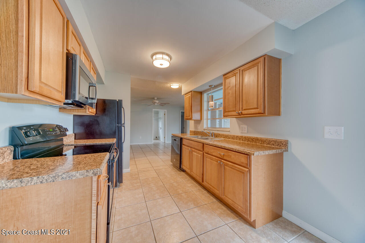 553 Edward Road West Melbourne, FL 32904 - Photo 17 of 26 a kitchen with stainless steel appliances granite countertop a stove a sink and a microwave