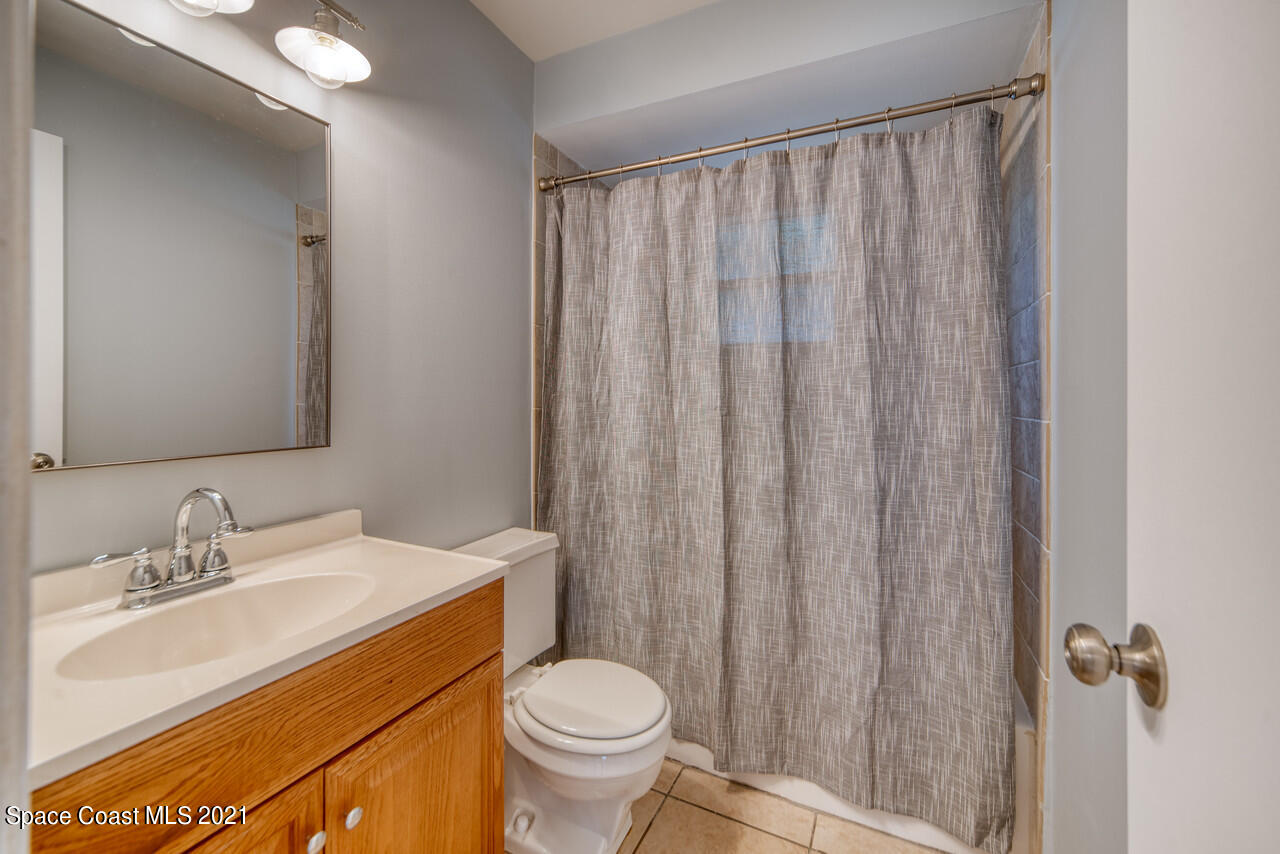 553 Edward Road West Melbourne, FL 32904 - Photo 20 of 26 a bathroom with a sink a toilet a mirror and shower curtain