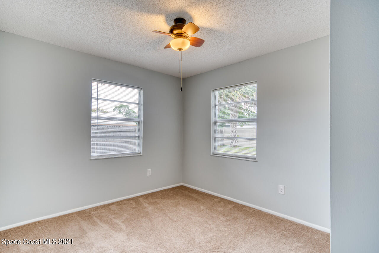 553 Edward Road West Melbourne, FL 32904 - Photo 21 of 26 an empty room with windows and chandelier fan
