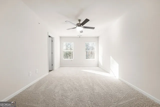 an empty room with windows and ceiling fan