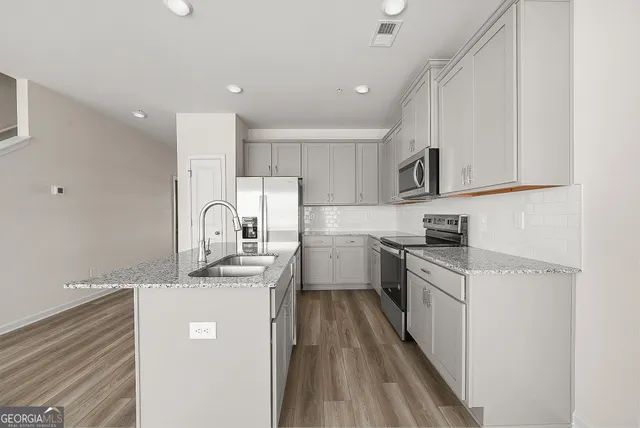 a kitchen with white cabinets appliances and sink