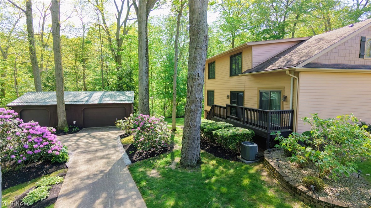 6409 Old Woods Road Ashtabula, OH 44004 - Photo 33 of 43 Private wooded setting featuring a two-car detached garage, paved driveway, and established landscaping