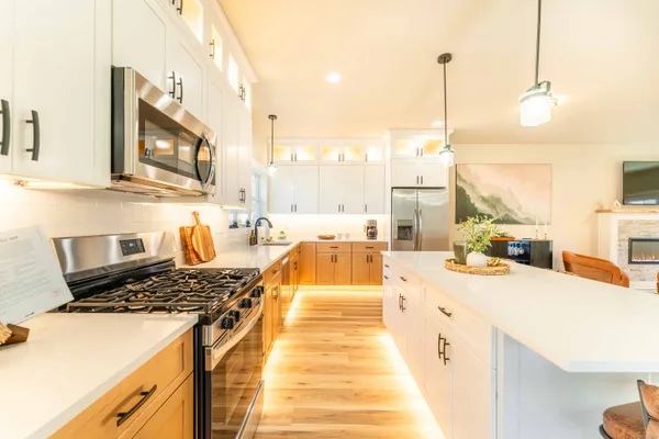 a large kitchen with stainless steel appliances a stove a sink dishwasher and a fireplace with wooden floor