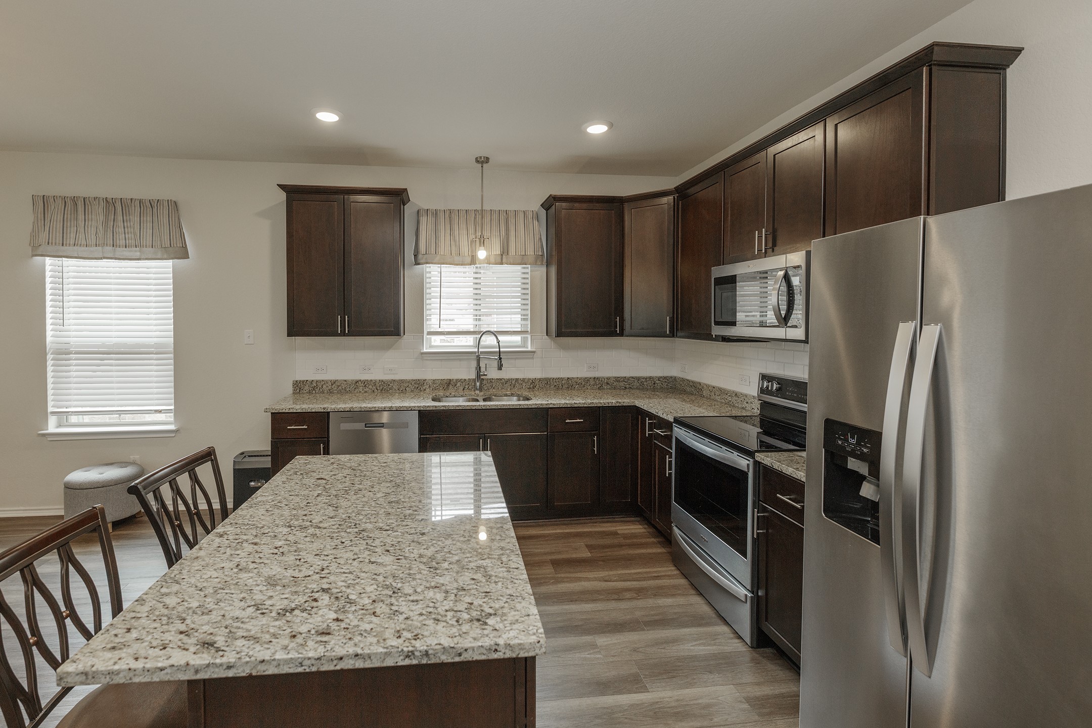 125 Janice Road Taylor, TX 76574 - Photo 5 of 26 Kitchen featuring wood-finish flooring, dark wood cabinetry, and light-colored countertops