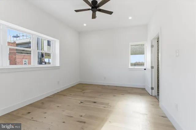 an empty room with a window and ceiling fan