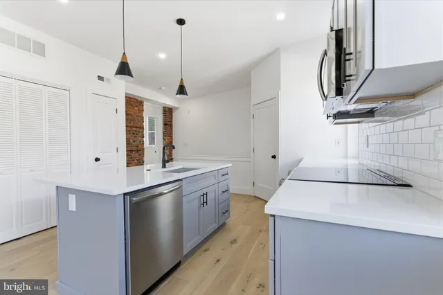 a kitchen with stainless steel appliances granite countertop a sink a stove and a wooden floors