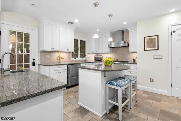 a kitchen with kitchen island granite countertop a sink a stove a counter top space and cabinets