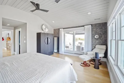 a bedroom with a bed and large windows