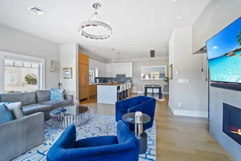 a living room with couches a coffee table and kitchen view with wooden floor