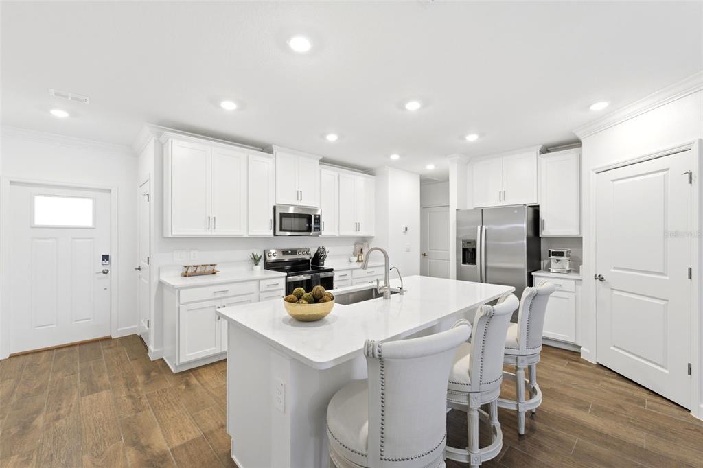 10799 Gable Dig Loop San Antonio, FL 33576 - Photo 5 of 19 a kitchen with refrigerator a stove and white cabinets with wooden floor