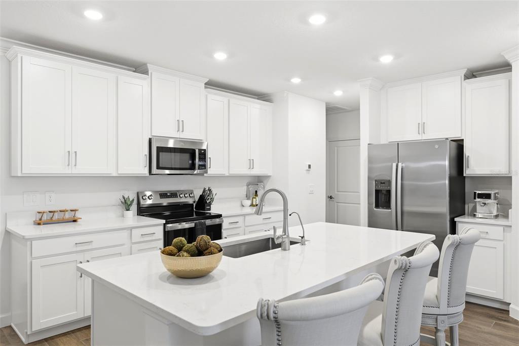 10799 Gable Dig Loop San Antonio, FL 33576 - Photo 6 of 19 a kitchen with a sink a stove and chairs