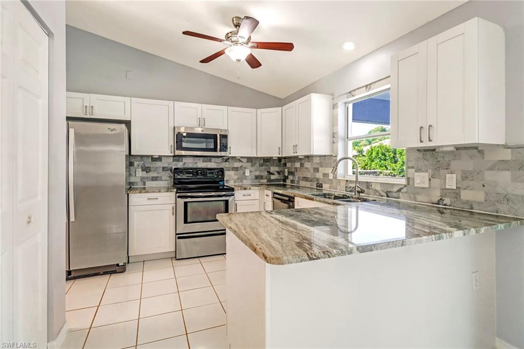 18250 Maple Road Fort Myers, FL 33967 - Photo 9 of 26 a kitchen with granite countertop a refrigerator a sink a stove top oven and a center island