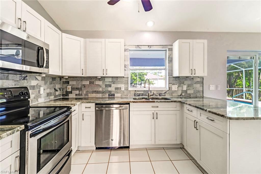 18250 Maple Road Fort Myers, FL 33967 - Photo 10 of 26 a kitchen with stainless steel appliances granite countertop a stove a sink and a microwave
