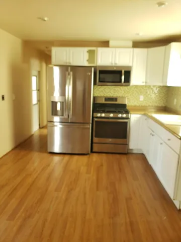 a kitchen with granite countertop a refrigerator stove oven and sink