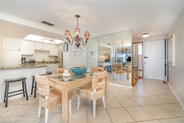 a dining hall with a dining table chairs and white kitchen view