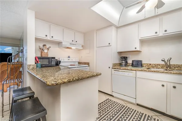 a kitchen with granite countertop a sink stove and cabinets