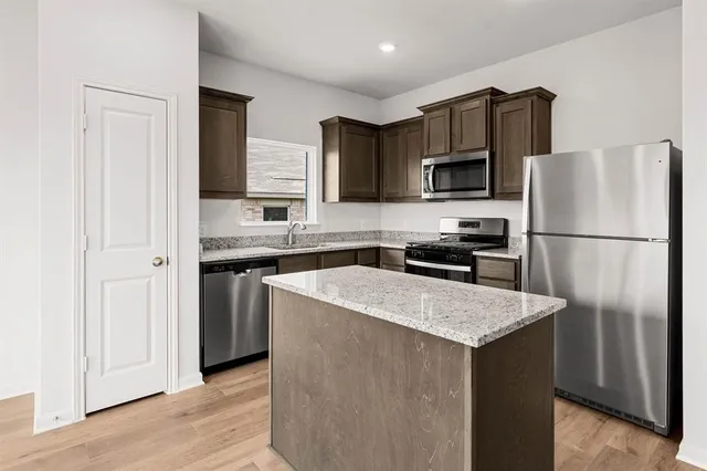 a kitchen with stainless steel appliances granite countertop a refrigerator a stove a sink and a microwave