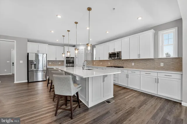 a kitchen with stainless steel appliances granite countertop a white cabinets and wooden floors