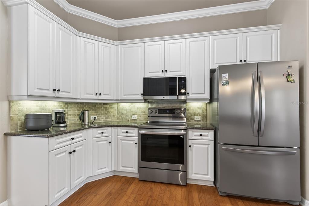 3762 Southwest 74th Drive Gainesville, FL 32608 - Photo 22 of 37 a kitchen with stainless steel appliances granite countertop a refrigerator stove a sink and white cabinets