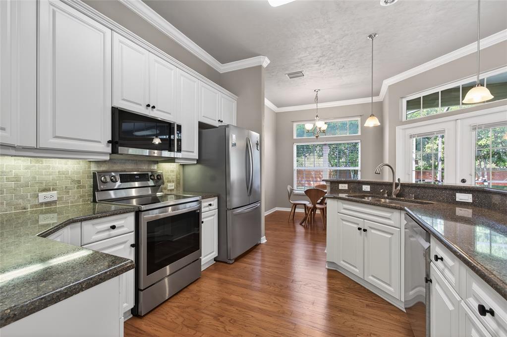 3762 Southwest 74th Drive Gainesville, FL 32608 - Photo 5 of 37 a kitchen with stainless steel appliances granite countertop a stove top oven a sink dishwasher a refrigerator and white cabinets with wooden floor