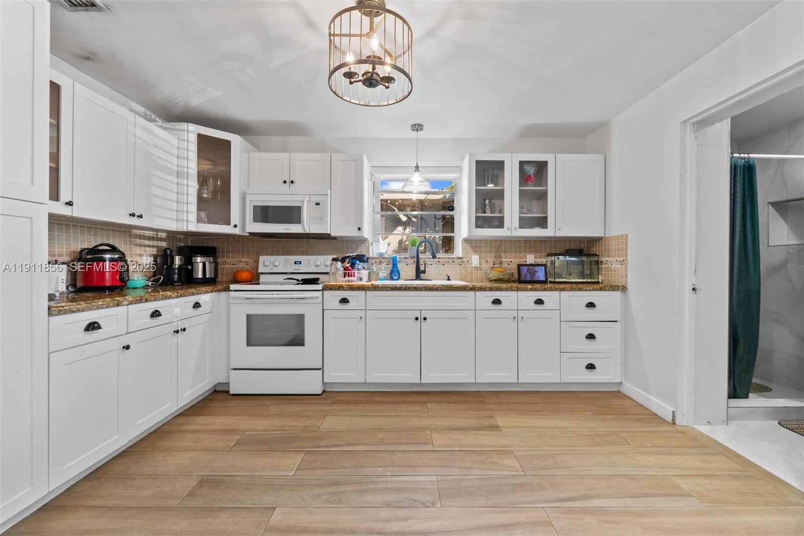 580 East 44th Street Hialeah, FL 33013 - Photo 18 of 41 a kitchen with cabinets stainless steel appliances and wooden floor