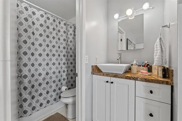 a bathroom with a granite countertop sink a toilet and a mirror