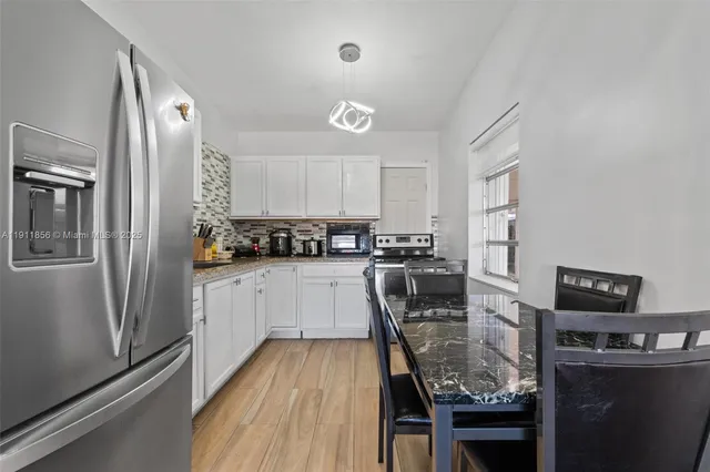 a kitchen with a refrigerator a stove a sink a dining table and chairs