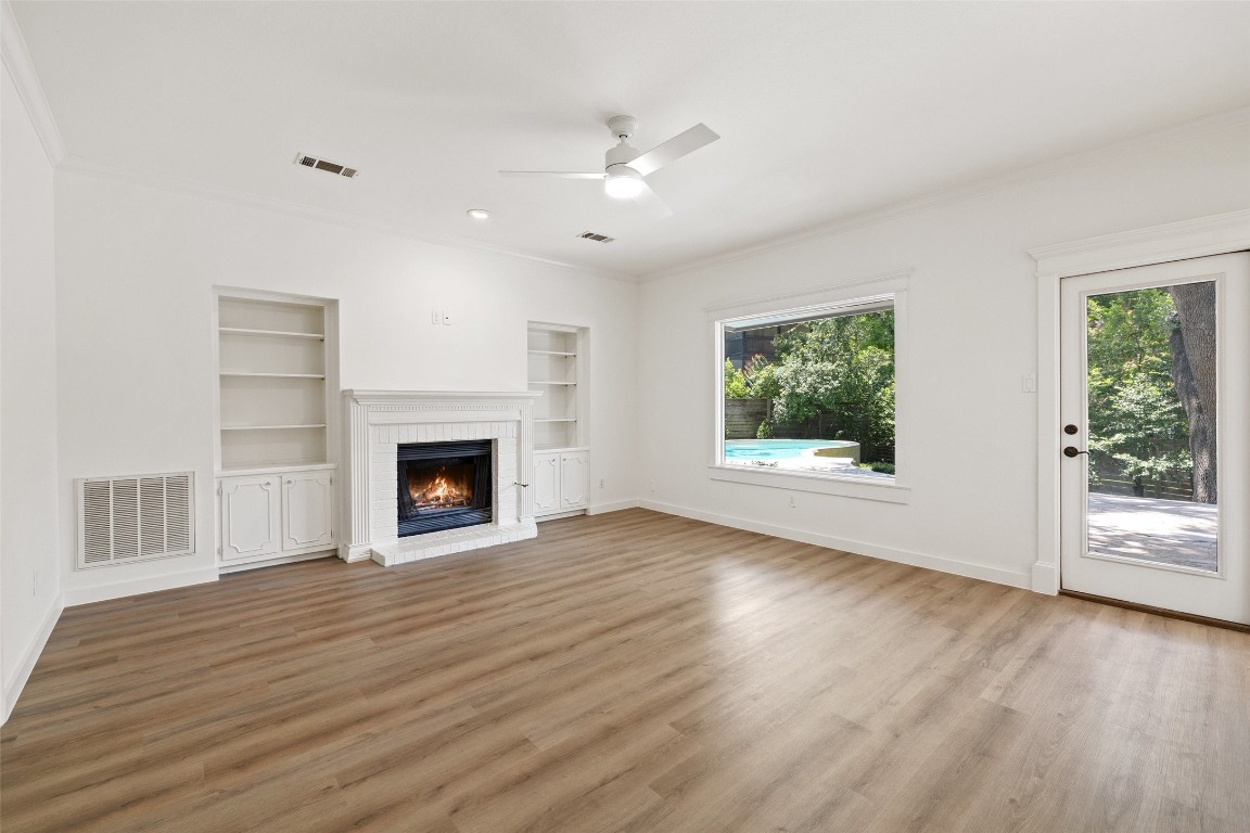 5700 Carry Back Lane Austin, TX 78746 - Photo 3 of 40 a view of an empty room with wooden floor fireplace and a window