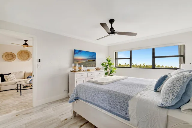 a bedroom with a bed a chandelier and flat screen tv