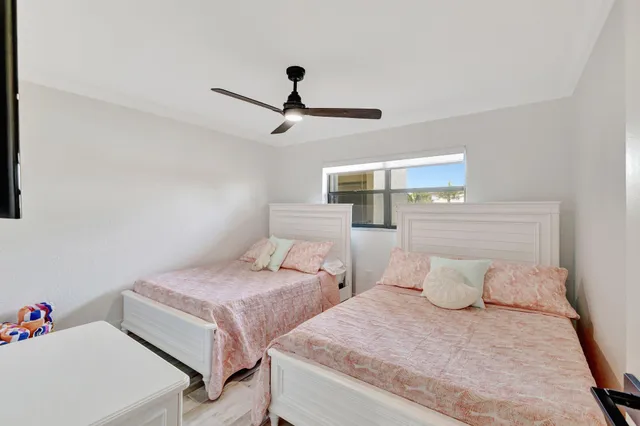 a bedroom with two beds and ceiling fan