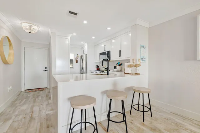 a kitchen with kitchen island a dining table chairs cabinets and wooden floor