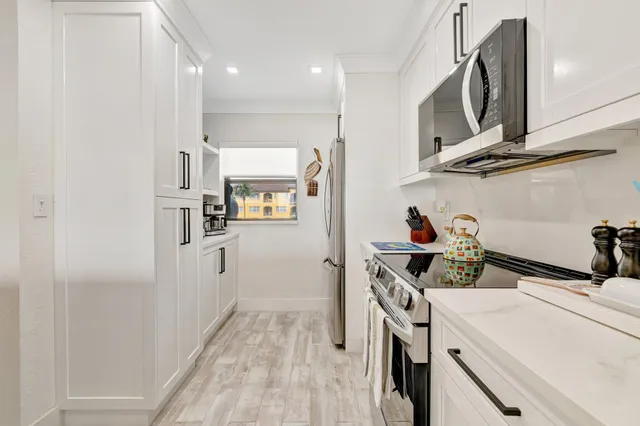 a kitchen with stainless steel appliances a refrigerator a sink a stove and white cabinets