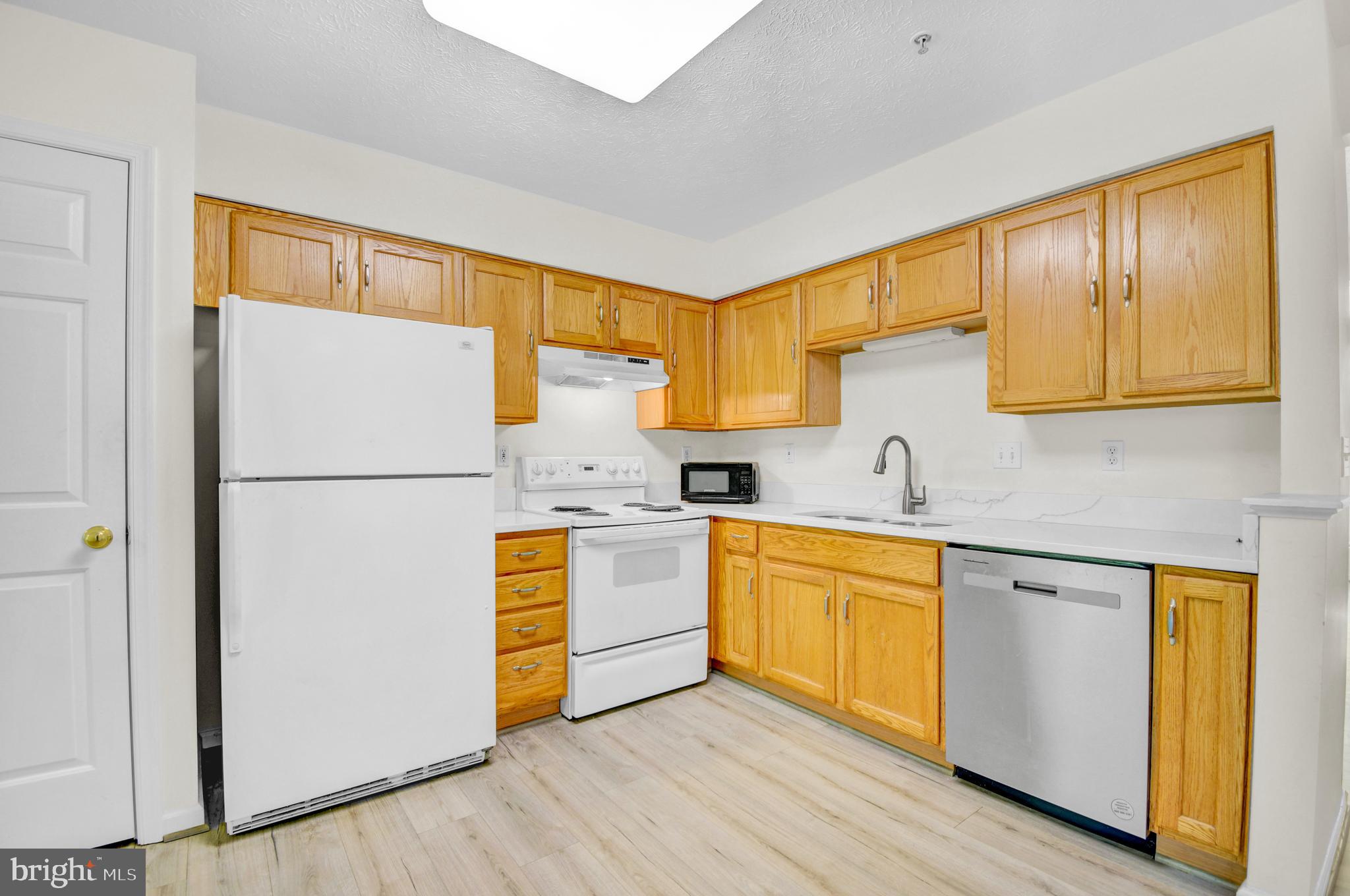 8036 Silver Fox Way Chesapeake Beach, MD 20732 - Photo 10 of 22 a kitchen with stainless steel appliances granite countertop a refrigerator a stove and a sink with wooden floor