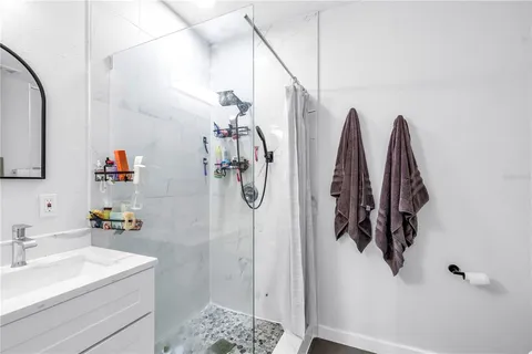 a bathroom with a sink vanity and shower