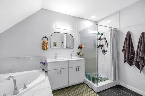 a bathroom with a bathtub sink mirror and shower