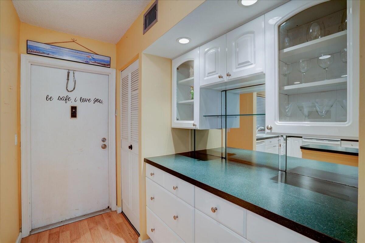 a kitchen with stainless steel appliances granite countertop a refrigerator a sink and white cabinets with wooden floor