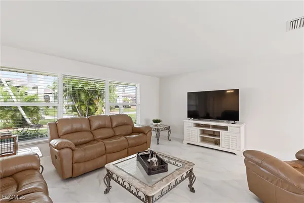 a living room with furniture a flat screen tv and a large window
