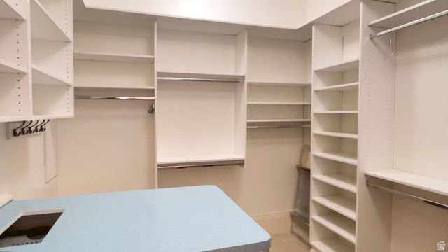 426 West Center Street Parowan, UT 84761 - Photo 32 of 107 Walk-in closet featuring white built-in shelving, multiple hanging rods, and a central island with a light blue countertop