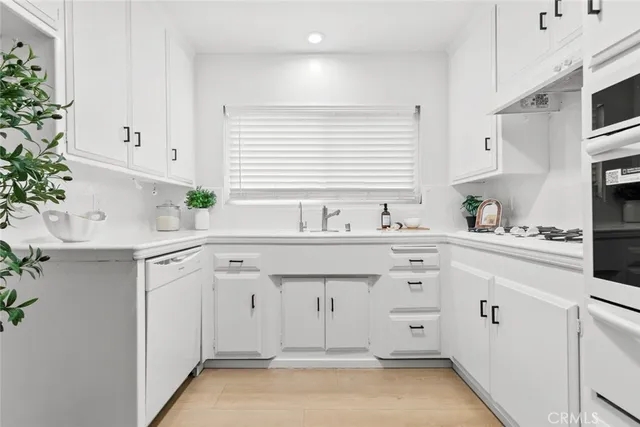 a kitchen with white cabinets and sink
