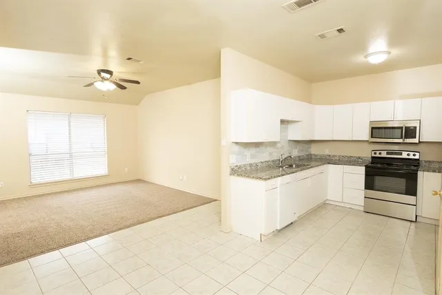 a kitchen with granite countertop white cabinets and white appliances
