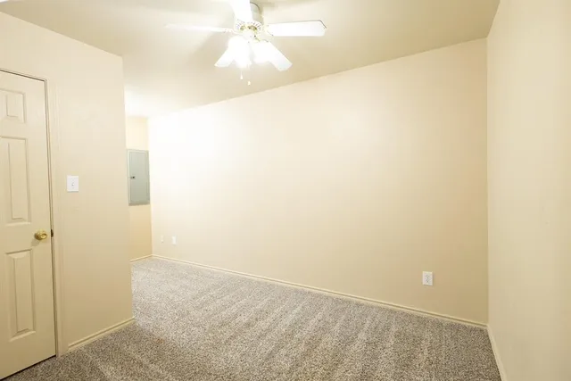 an empty room with a ceiling fan and a shower