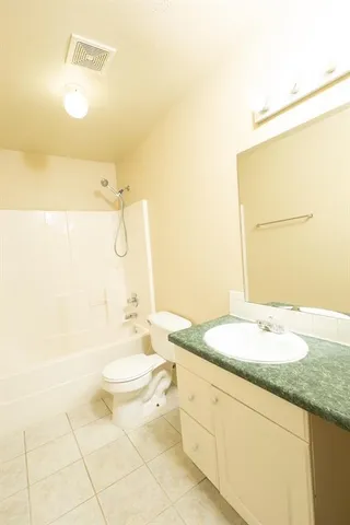 a bathroom with a granite countertop sink mirror vanity and toilet