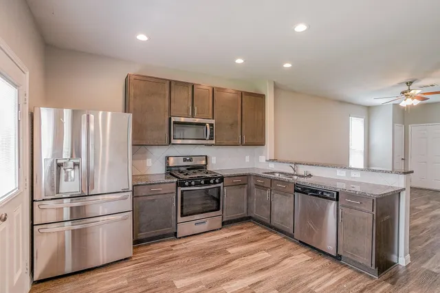 a kitchen with stainless steel appliances granite countertop a sink stove and refrigerator