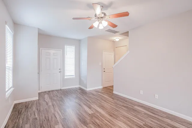 a view of a room with wooden floor and a ceiling fan