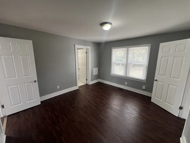 an empty room with wooden floor and windows