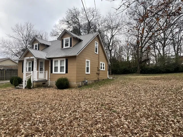 a view of a white house with a yard and large tree